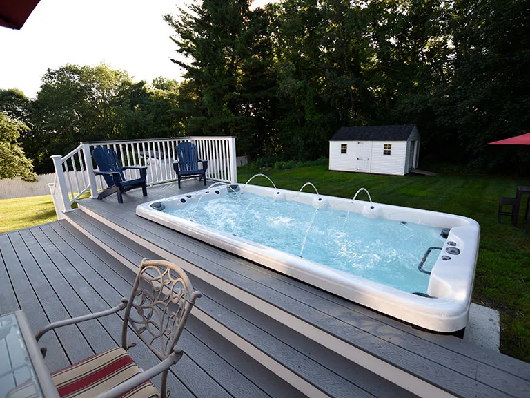Swim spa installed in a backyard deck with patio furniture