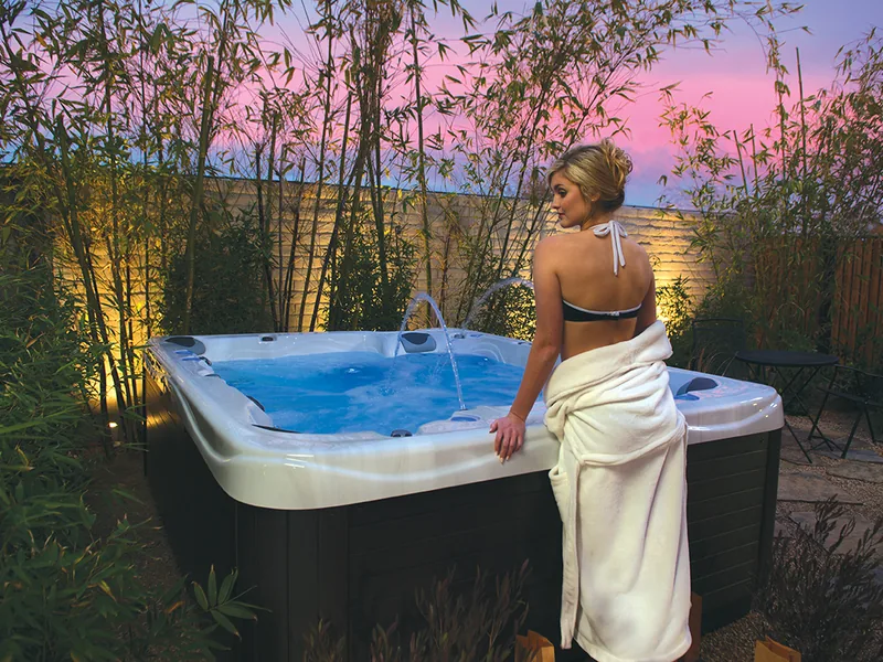 Woman stepping out of a hot tub at sunset